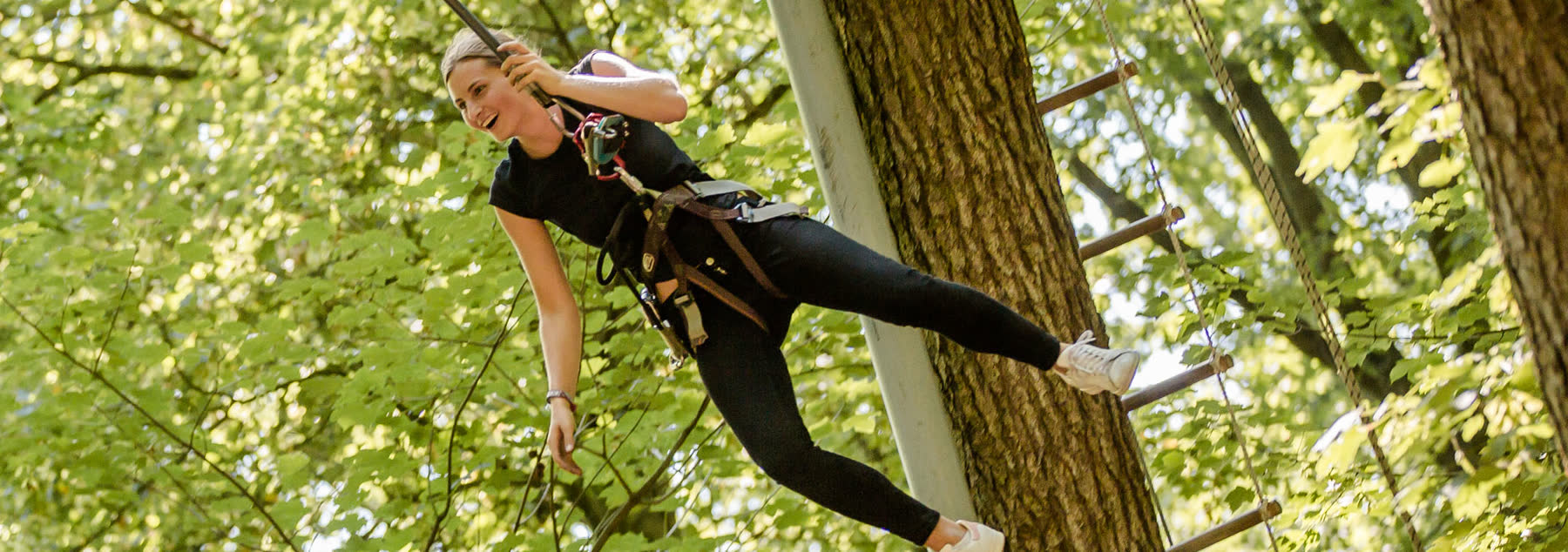 Woman swinging through the forest on the Big Swing with her legs stretched out