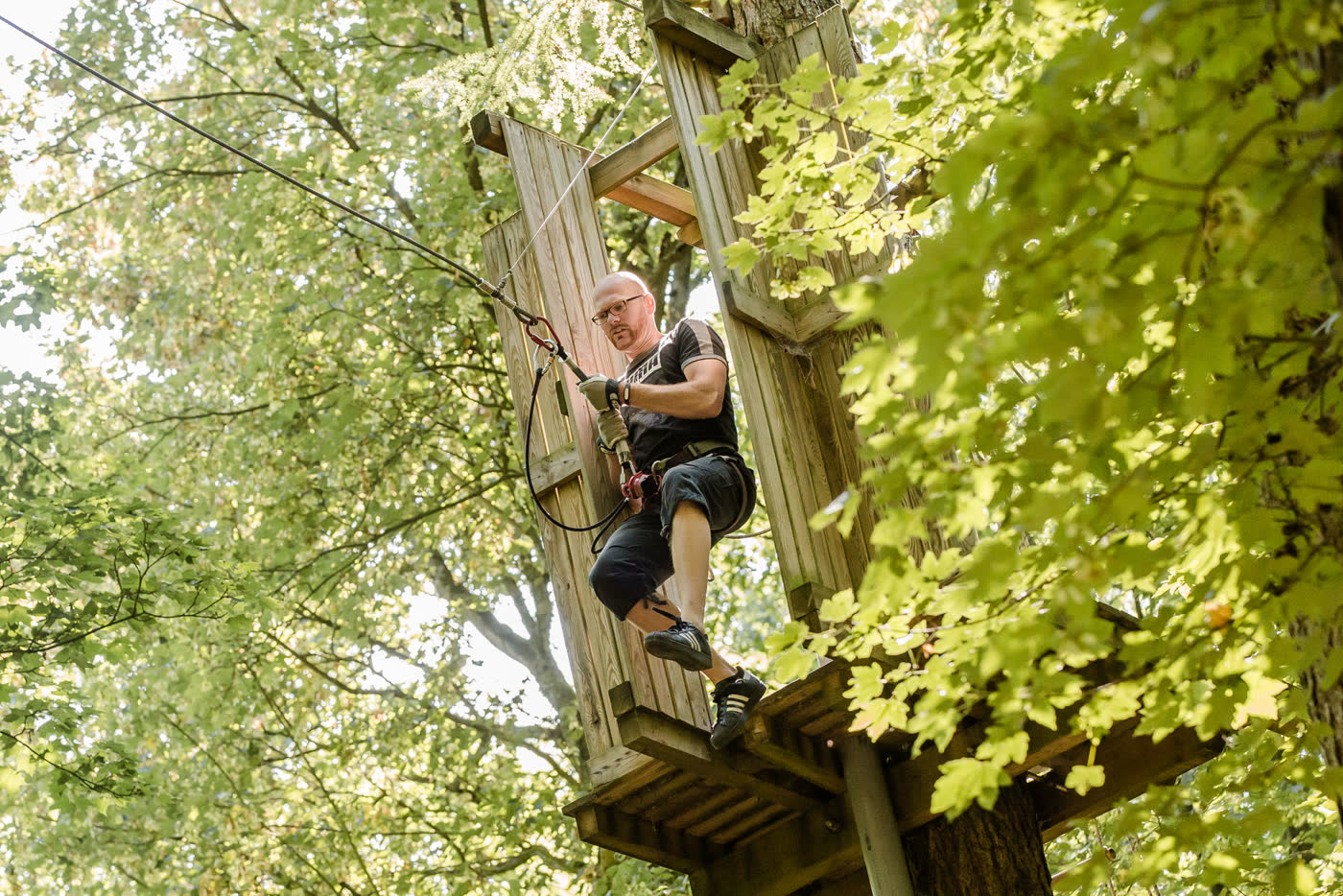 Man standing on the wooden platform of the Big Swing, holding the vine